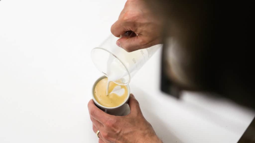 Pouring milk into a Flat White cup from Loveramics